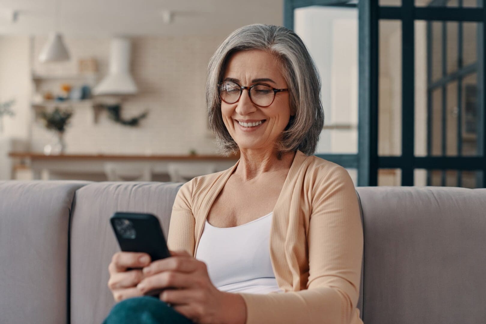 A woman sitting on the couch looking at her phone.