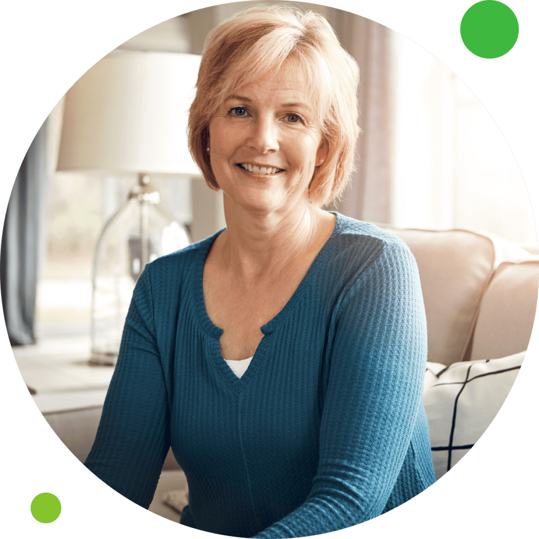 A woman sitting in front of a green background.