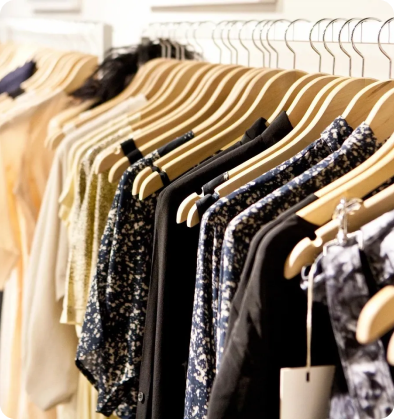 A row of clothes hanging on wooden hangers.