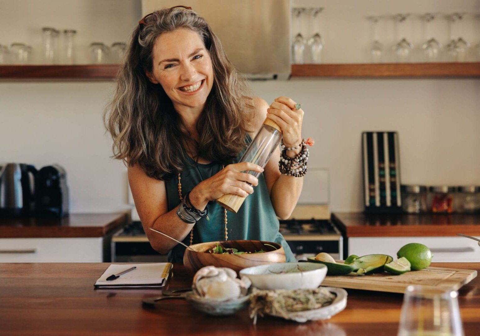 A woman is smiling while preparing food in the kitchen.