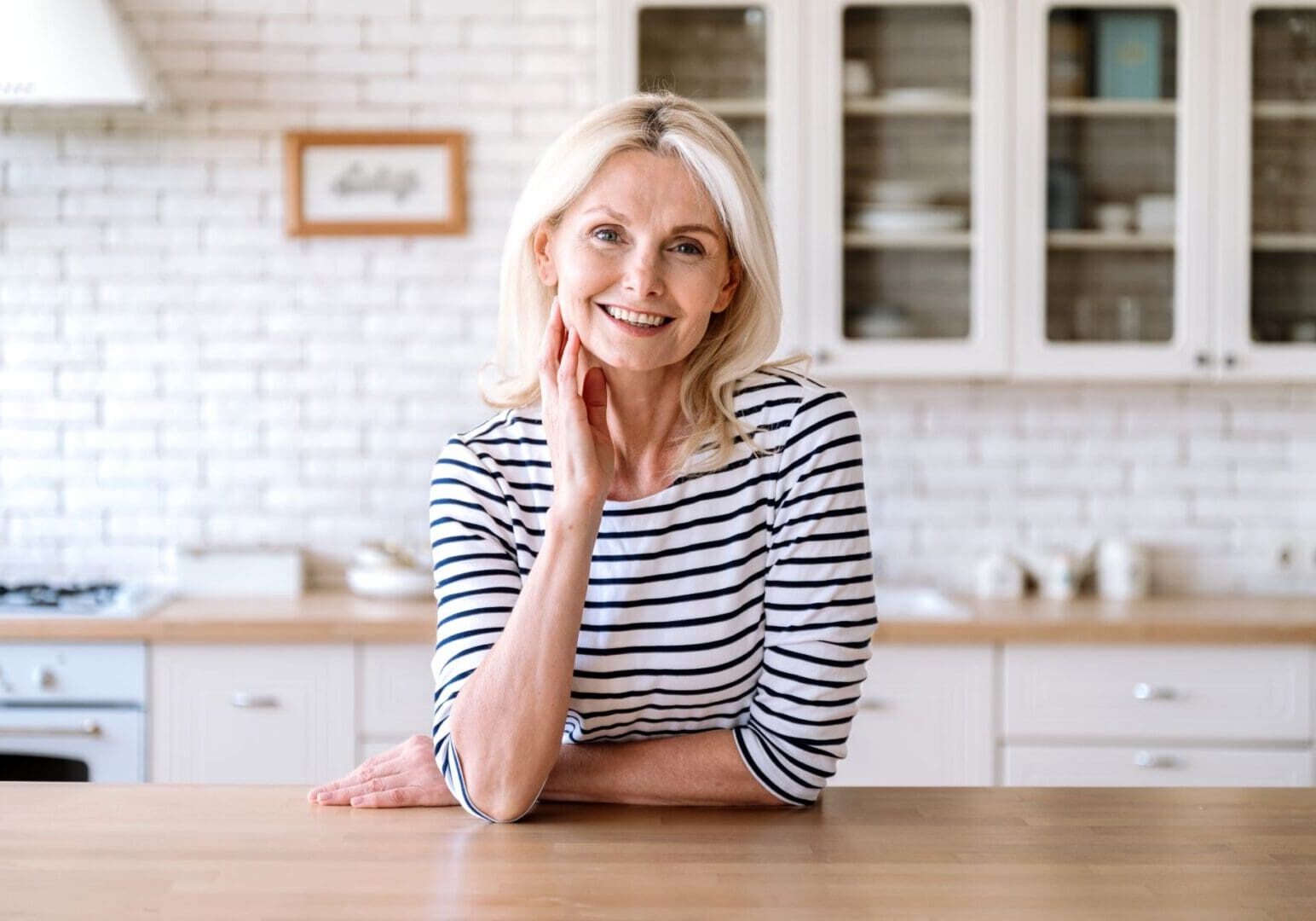 A woman sitting at the table in her kitchen.